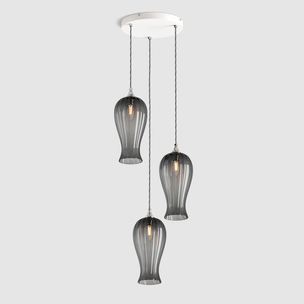 Group of Long ribbed grey coloured glass decorative pendant lights with brass fitting and fabric covered flex, hanging on a ceiling plate