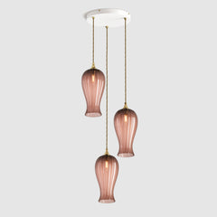 Group of Long ribbed pinky tea coloured glass decorative pendant lights with brass fitting and fabric covered flex, hanging on a ceiling plate