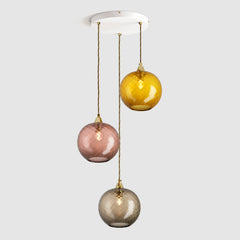 Group of warm amber and brown diamond sphere glass pendant lights on ceiling plate with brass fittings and fabric covered flex