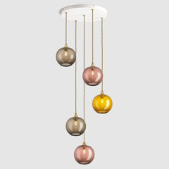 Group of warm amber and brown diamond sphere glass pendant lights on ceiling plate with brass fittings and fabric covered flex