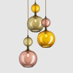 Group of round amber, olive and tea glass pendant lights with decorative metal and fabric covered flex on a ceiling plate