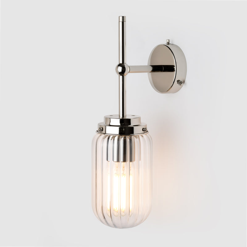 Clear ribbed glass light shade on a polished nickel wall arm
