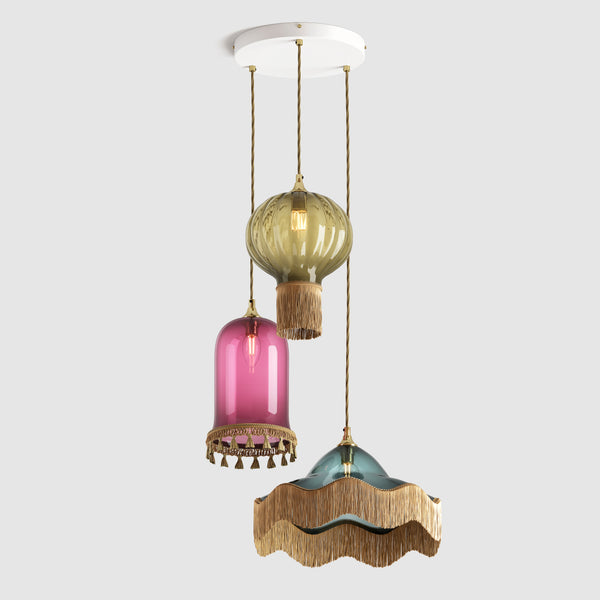Group of coloured glass decorative pendant lights with fabric lamp fringe and twisted flex hanging on a ceiling plate